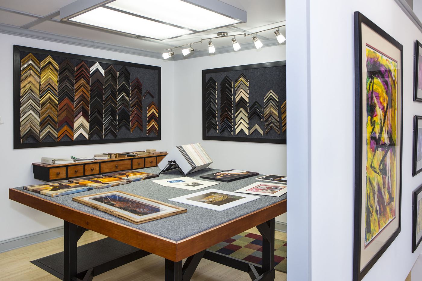 Inside the H&H design room — walls of frame moulding samples and a worktable with prints