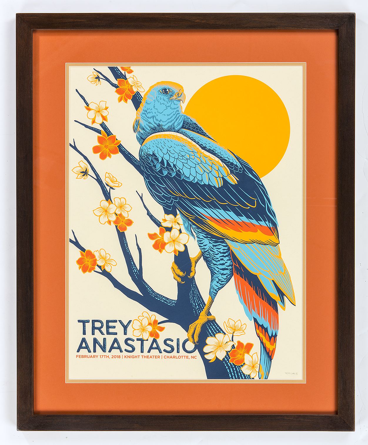 Concert poster custom framed with an orange mat and dark wood frame by H&H Custom Framing